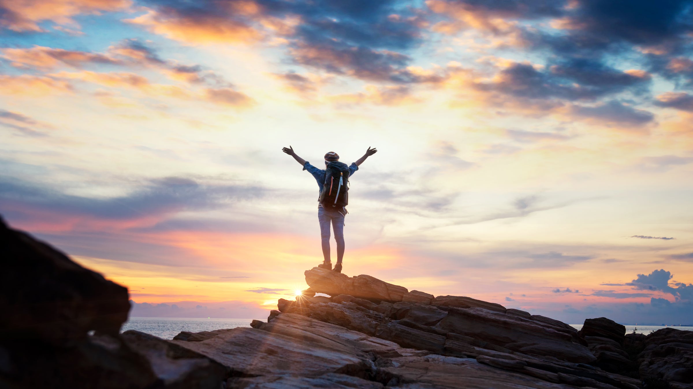 female hiker on top of mountain at sunset