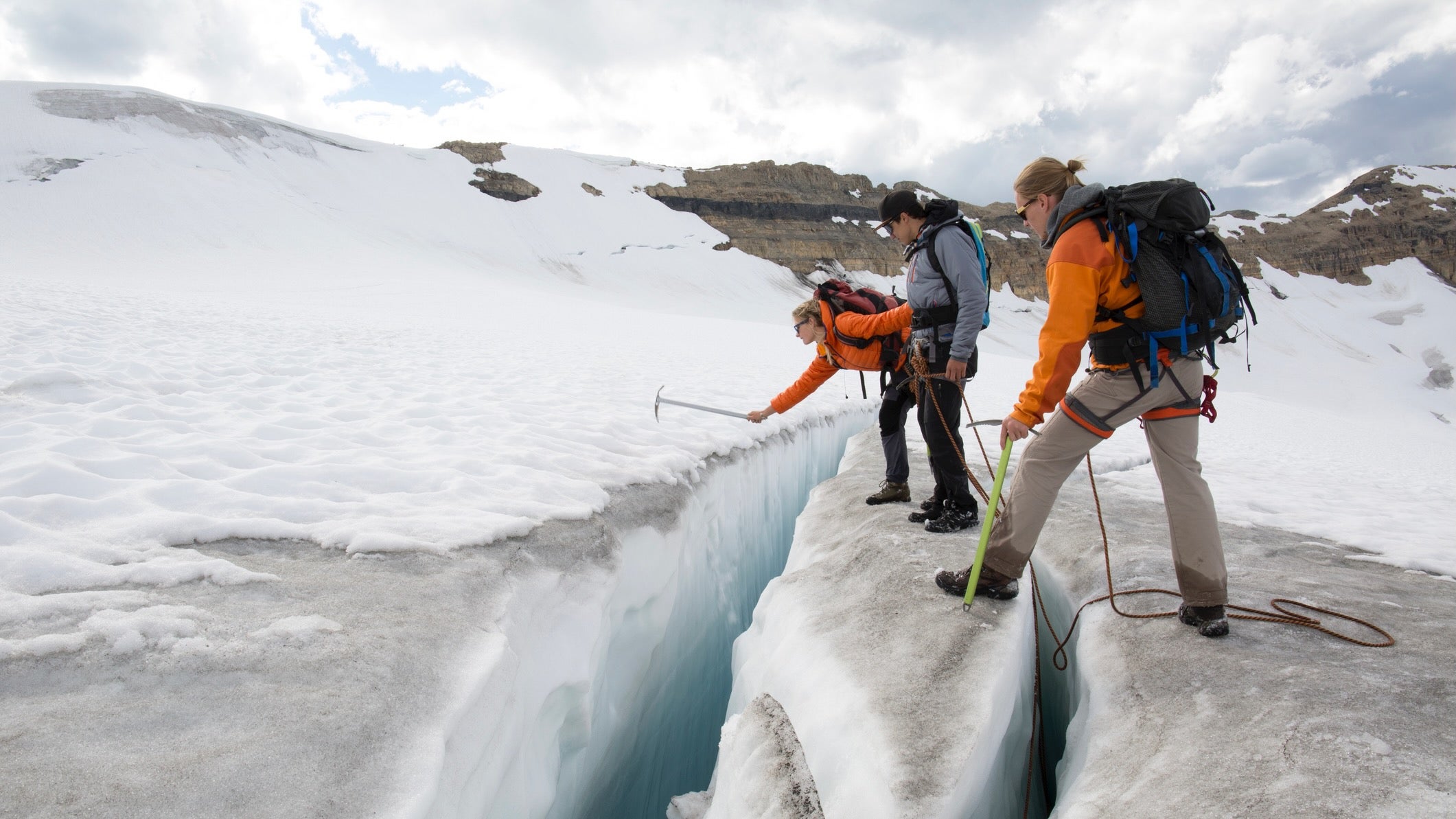 Three mountaineers test crevasse edge on glacier crevasse
