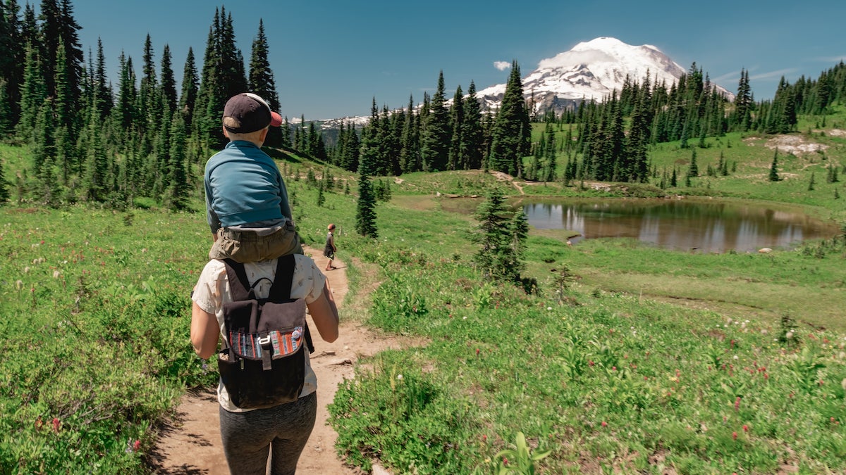 Young mother carrying son toward Mt Rainier on the Naches Peak Loop Trail in Mt. Rainier National Park.