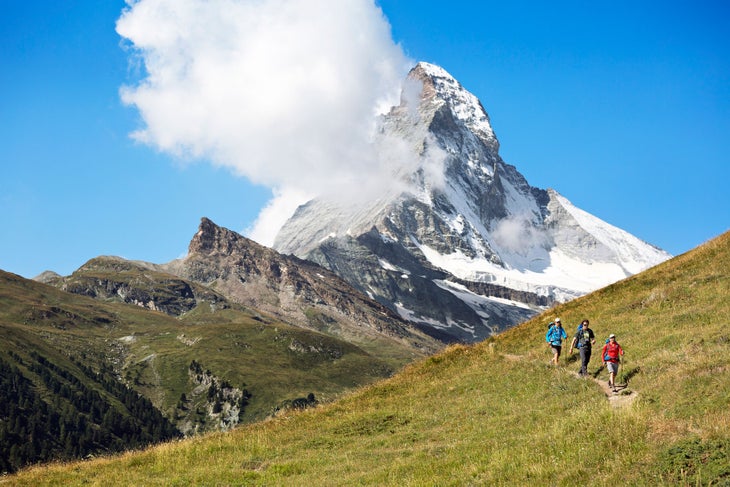 The Matterhorn Three hikers on a grassy trail with the Matterhorn above on the sixth, and final day of the Chamonix to Zermatt Glacier Haute Route.