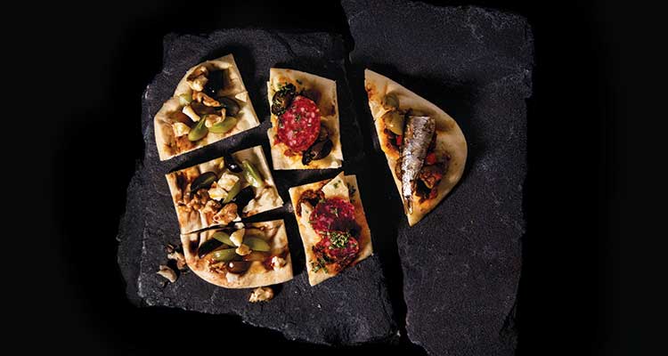 "an image of tapas on a black stone."