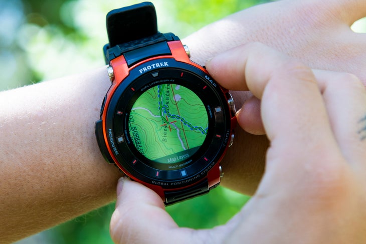 20190710_ViewRanger_727 Close up shot of white hands adjusting the ViewRanger app on a black and orange Casio ProTrek watch. A green topographic map with a blue route…