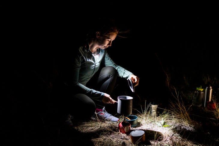 Petzl_strange_14_sous chef Women using camp cook-wear at night with headlamp around her neck.