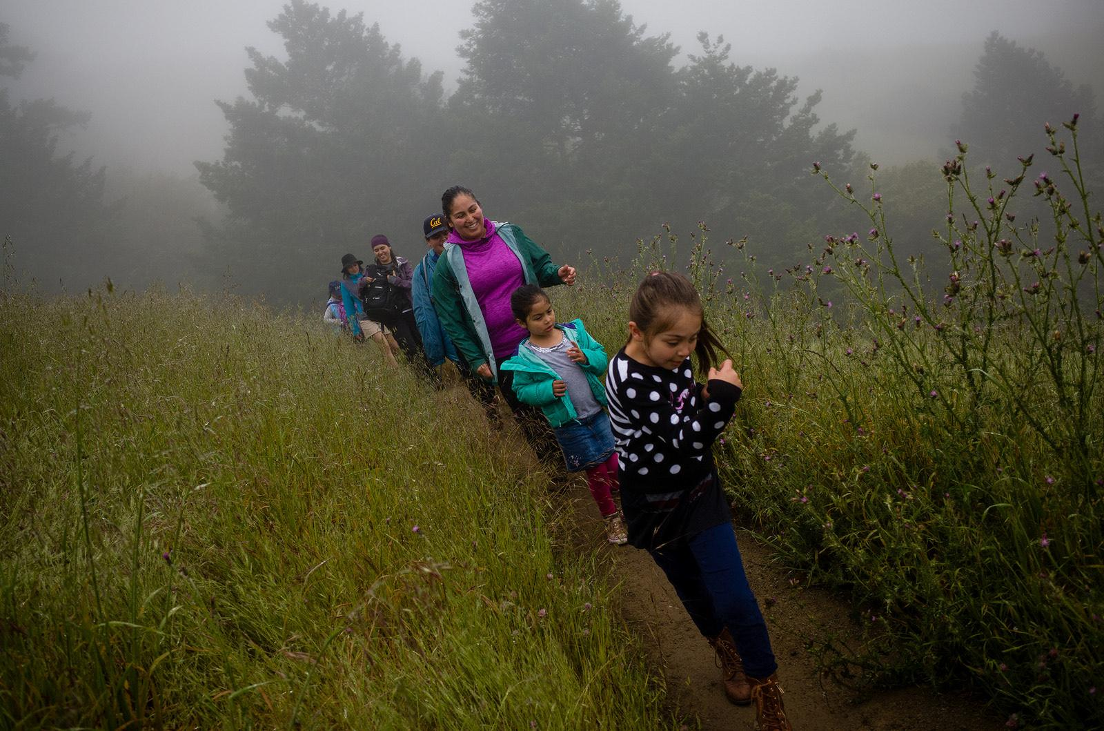 "hiking group with kids on misty trail"