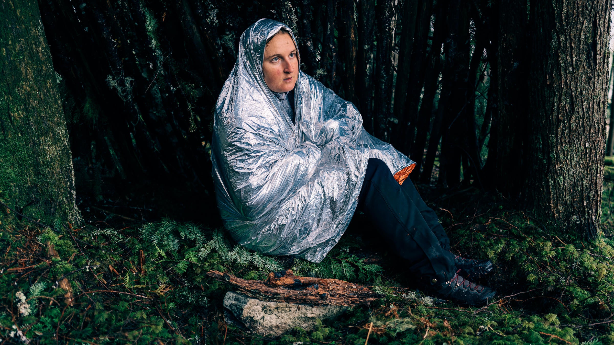 A hiker wrapped in a space blanket on a mossy background