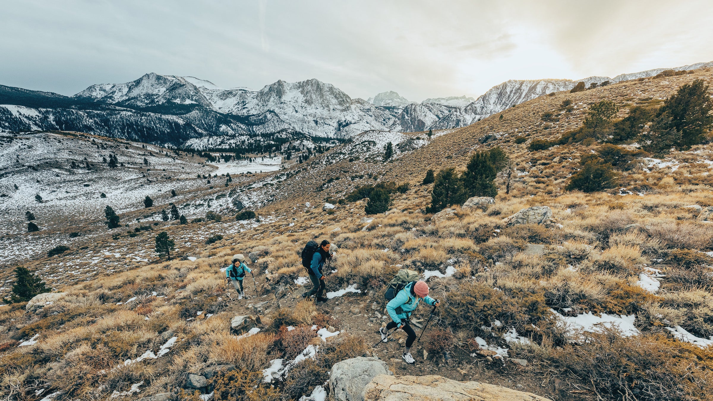 Three hikers on a trail in mountains