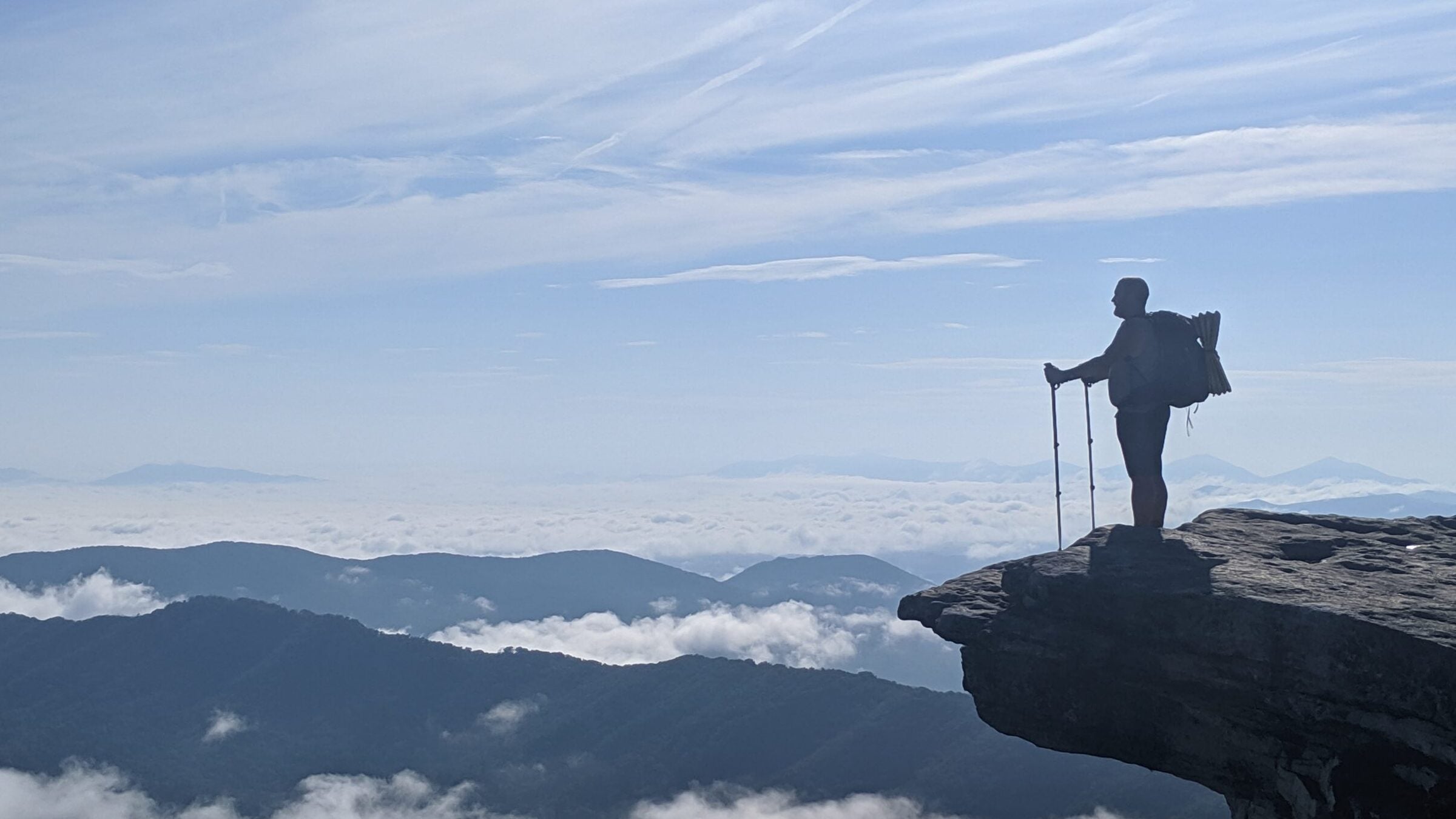 Andy Niekamp on Mcafee Knob on the AT, on a ledge with mountains in the background