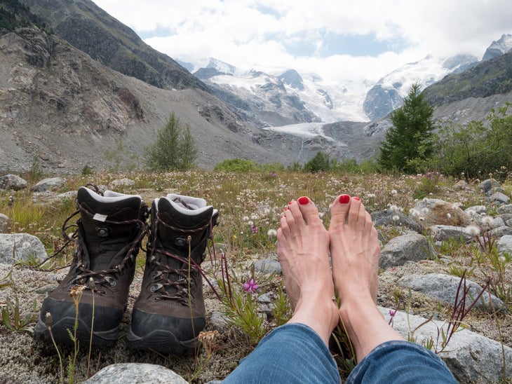 Woman taking off hiking boots and is relaxing after hiking.