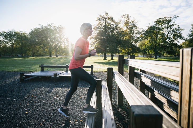 Woman doing step-ups in an outdoor park.
