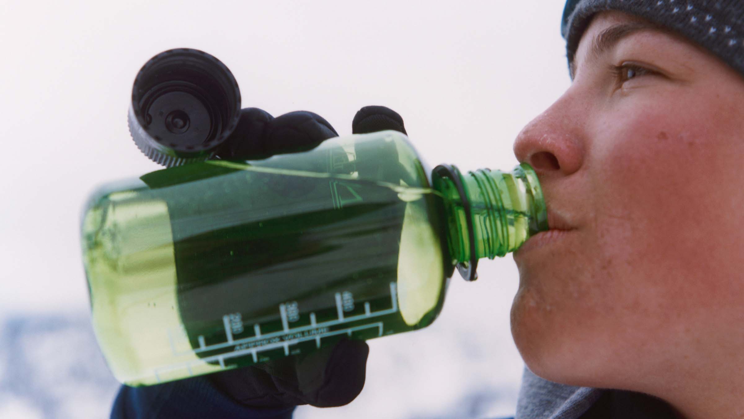 person drinking from water bottle in winter