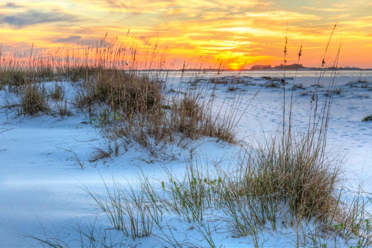 A colorful sunset over the sea and dunes of Fort Pickens Beach in the Gulf Islands National Seashore, Florida.