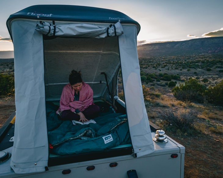 dani mortell reads her book from inside her scout camper