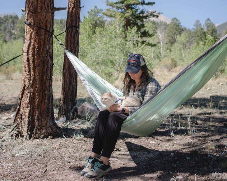 dani pets her cat while sitting in a hammock