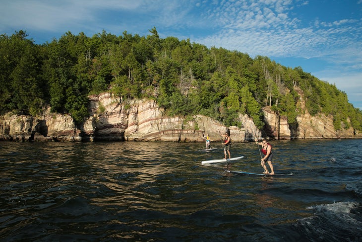 three people paddle boarding in vermont