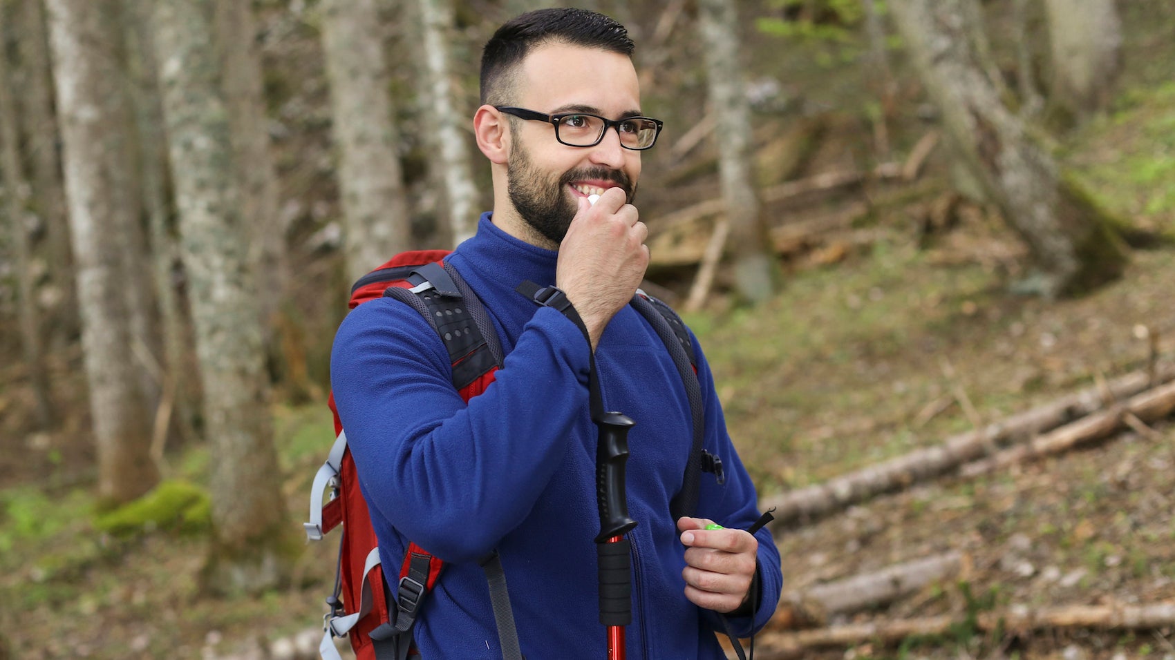 Young man hiking in woods, using lip balm for protection.