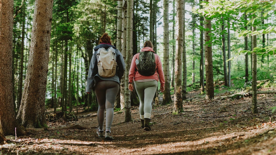 Two females hiking in the forest.