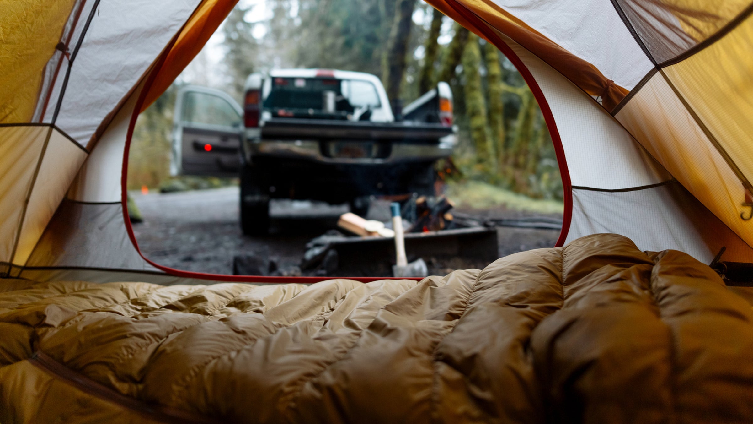 sleeping bag in a tent next to a truck