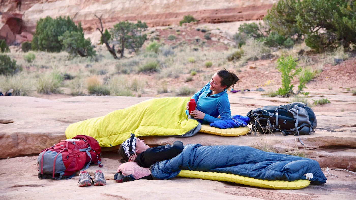 Two women camping below the towering walls of The Maze section of Canyonlands National Park, Utah.