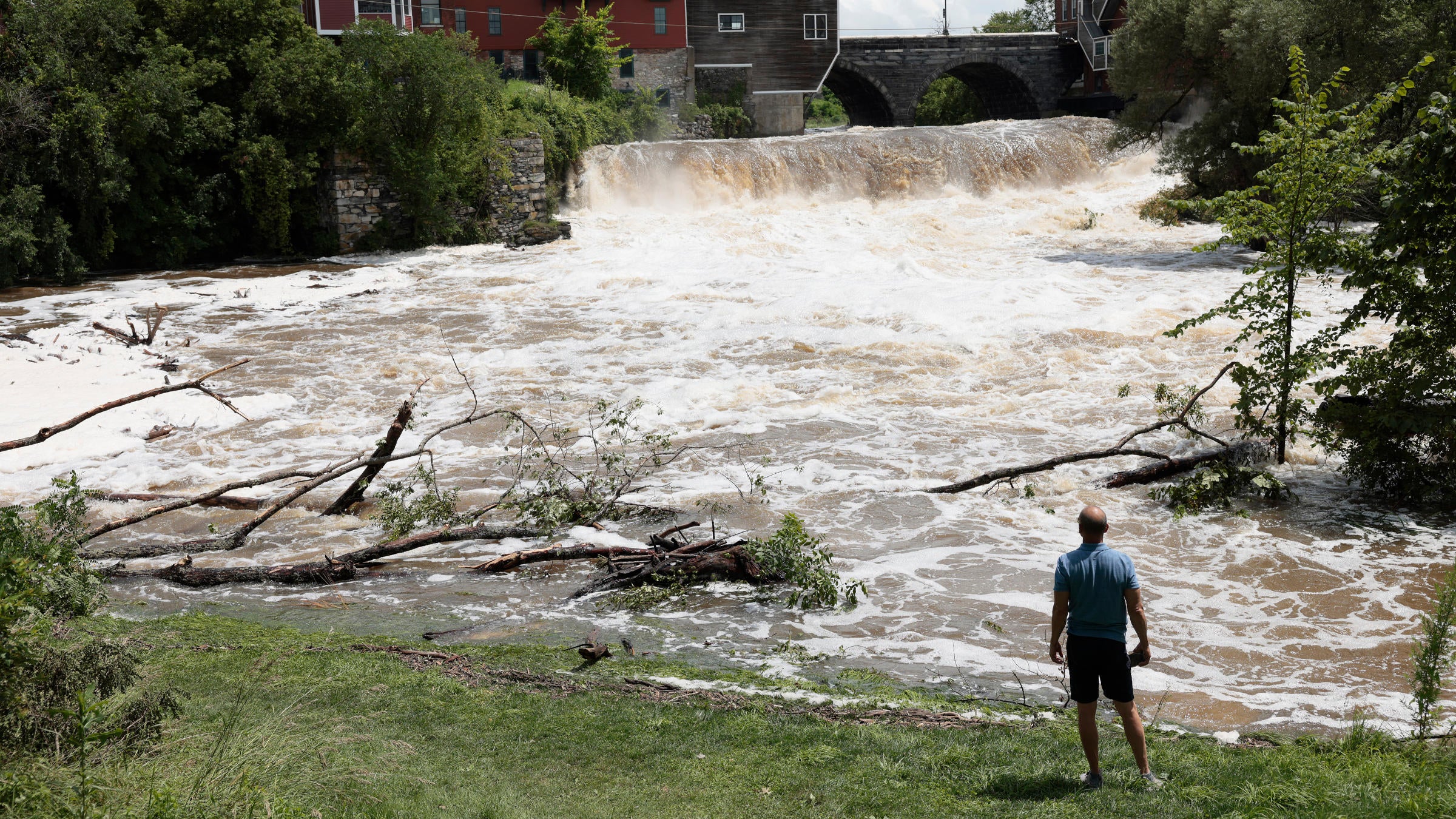 a creek overflows its banks as a man watches