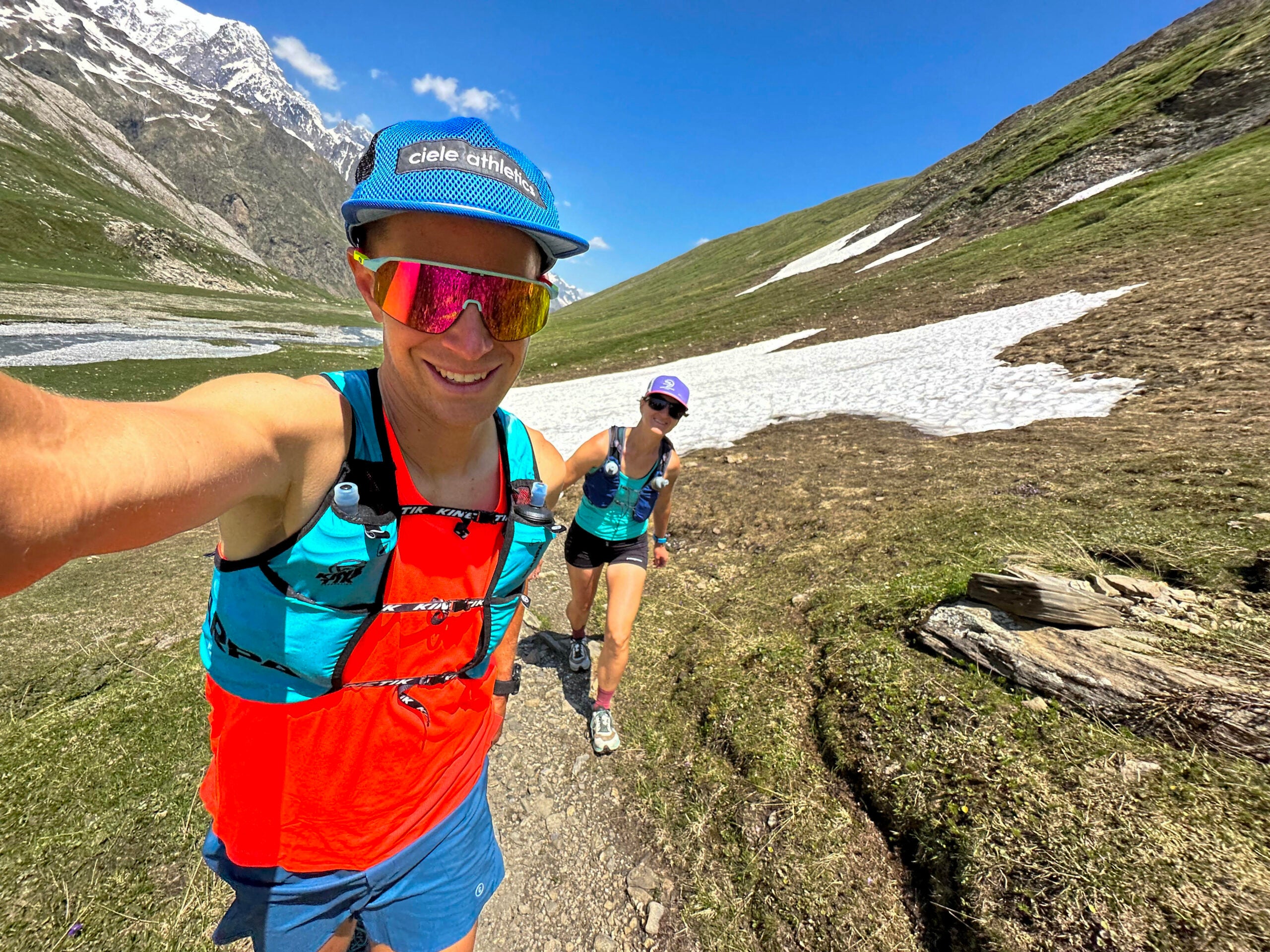 Selfie by ultra-marathoner Gabe Joyes with his wife Jenny running on a mountain trail with a snow field