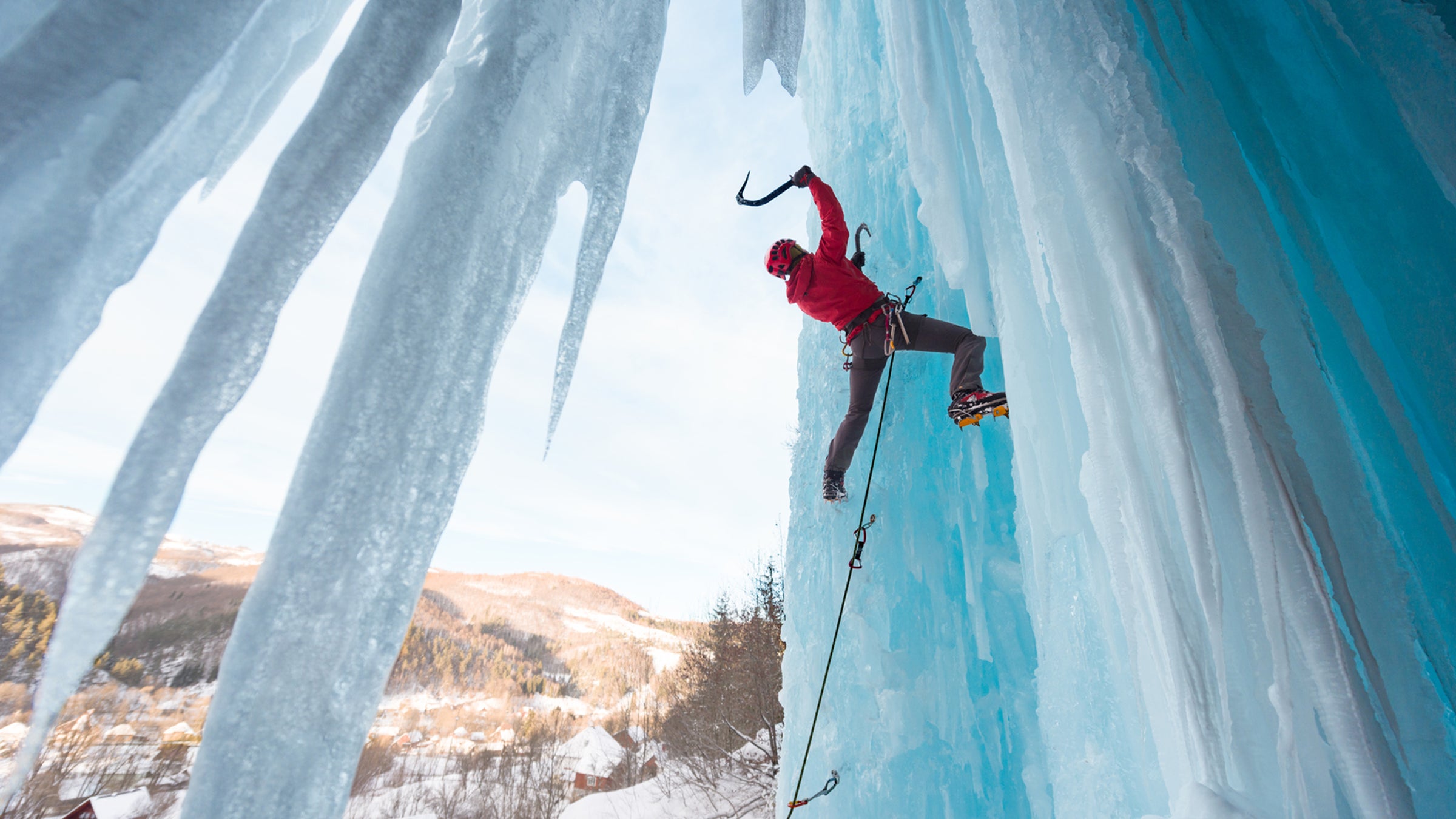 Strong woman ice climbing on frozen waterfall on a beautiful winter day