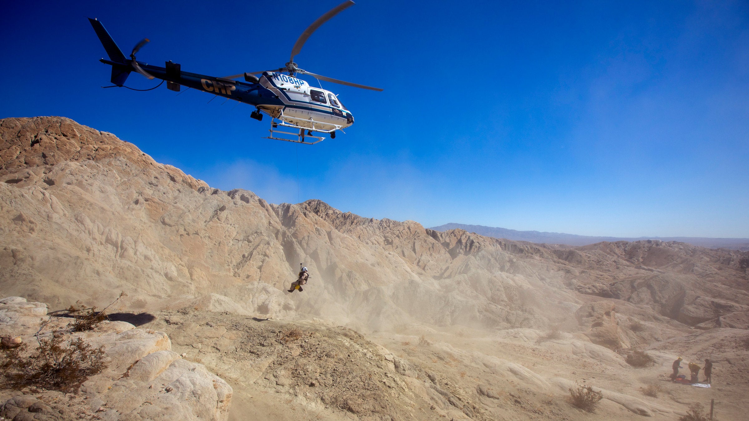 helicopter airlifting injured hiker over desert mountain