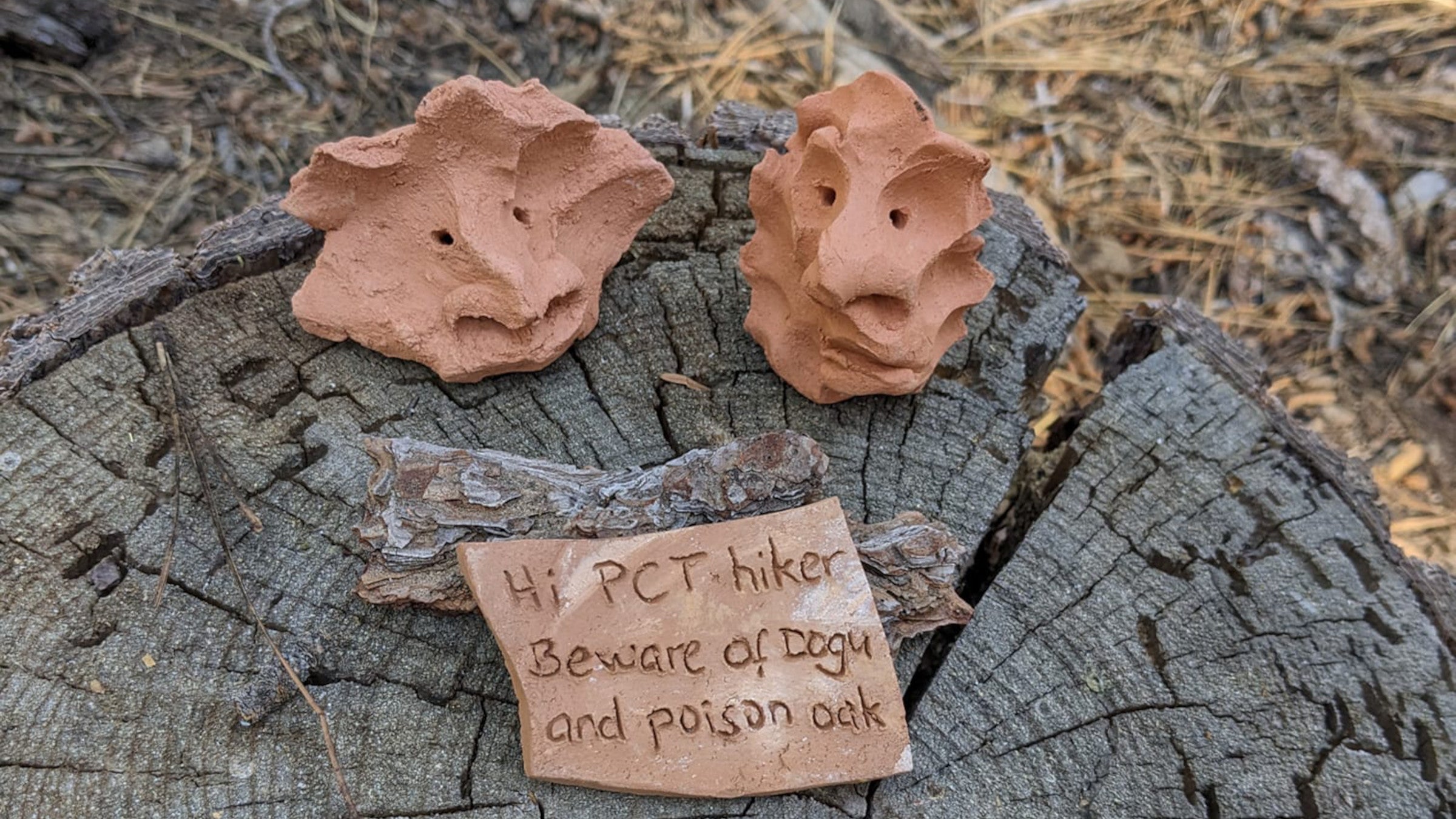 two small clay figurines on a stump