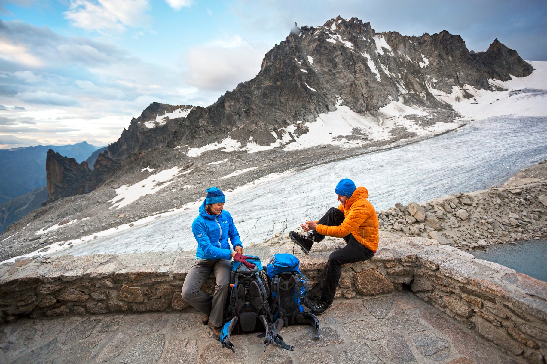 Couple preparing to leave hut Two hikers sitting on the deck of the Cabane d'Orny tying shoes and getting ready to leave for the second day of the Chamonix to Zermatt Glacier…