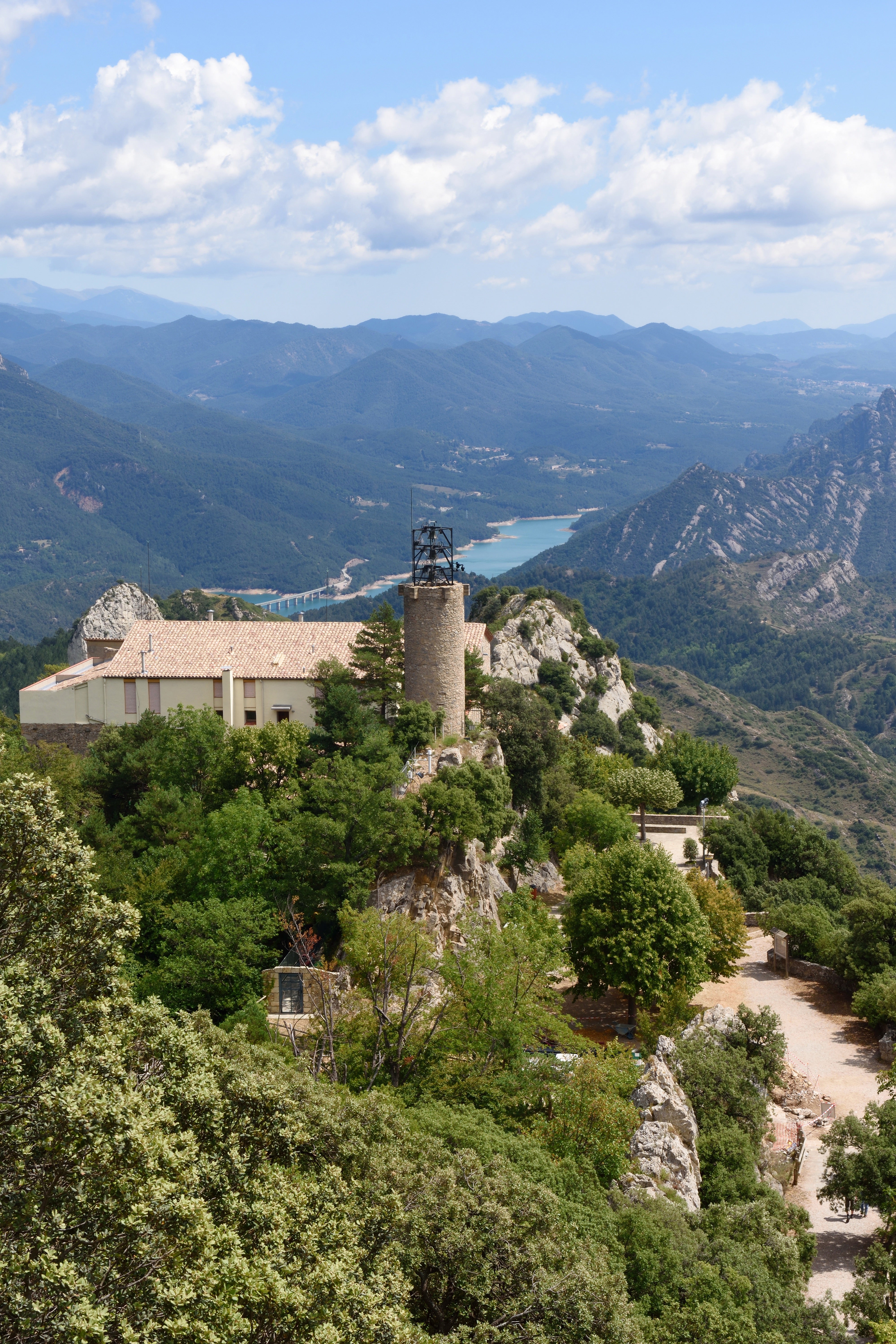 Queralt sanctuary @CTB_Inmedia solutions Queralt Sanctuary, a stone building, sits on a hill with the mountains and aqua river of the Cami des Bon Homes trail in Catalonia.