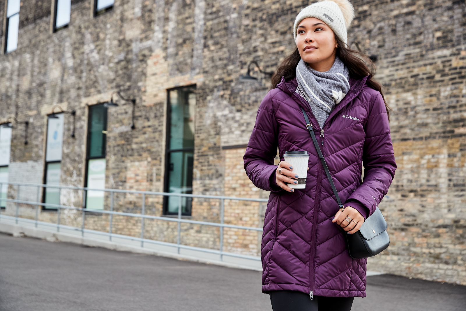 DicksColumbia Women in purple Columbia jacket holding coffee in the street.